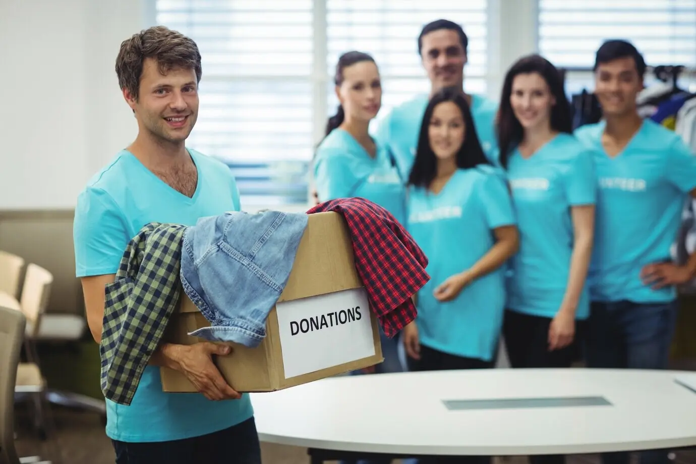 A volunteer holding clothing inside a donation box.