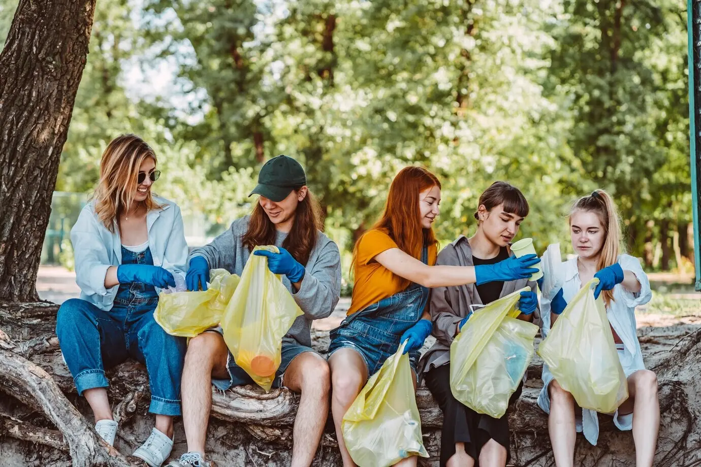 A group of activist friends picking up plastic litter in a park. Environmental conservation.